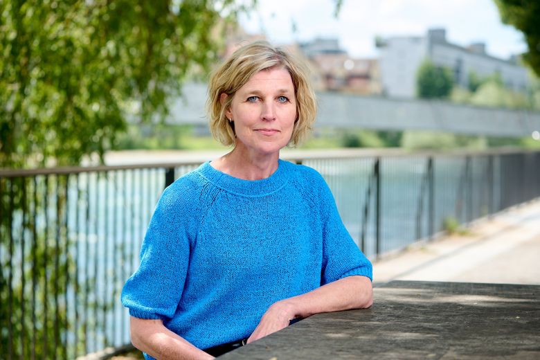 Blonde Frau mit blauem Pullover.