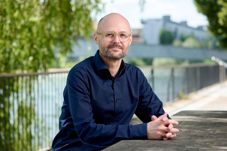 Mann mit blauem Hemd an einem Fluss.